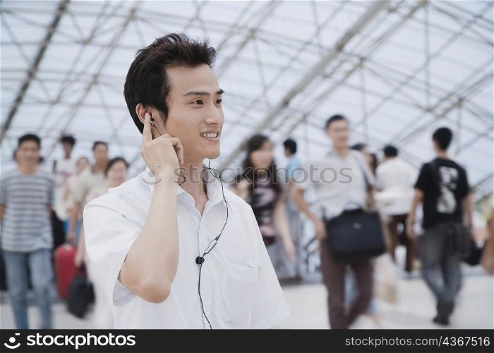 Close-up of a young man standing in a corridor and listening to music