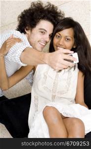 Close-up of a young man taking a picture of himself and a young woman with a mobile phone