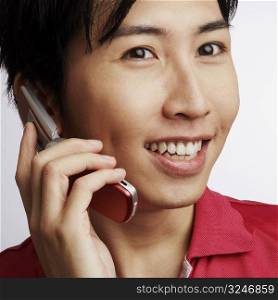 Close-up of a young man talking on a flip phone