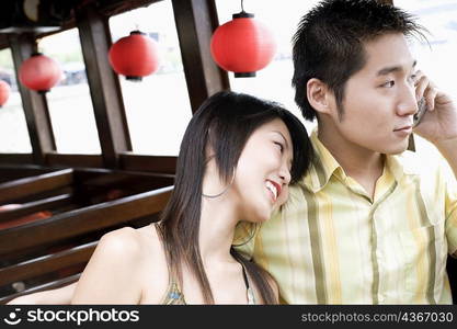 Close-up of a young man talking on mobile phone and a young woman resting her head on his shoulder