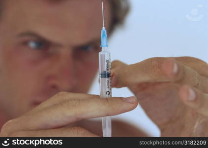 Close-up of a young man tapping a syringe