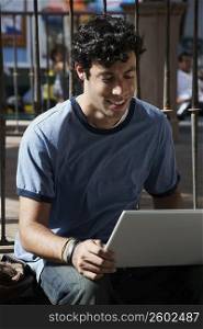 Close-up of a young man using a laptop and smiling