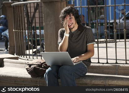 Close-up of a young man using a laptop and smiling