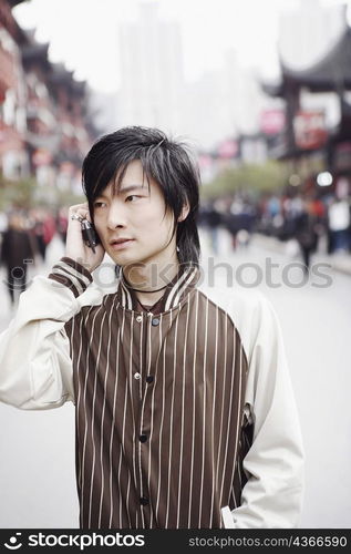 Close-up of a young man using a mobile phone with his hands in his pockets