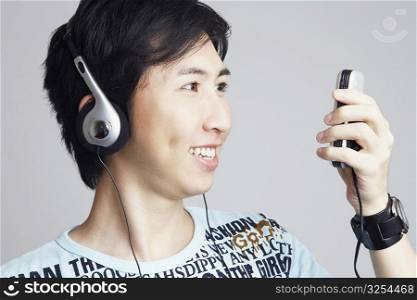 Close-up of a young man wearing headphones and holding a mobile phone