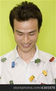 Close-up of a young man with paper clips on his shirt and smiling