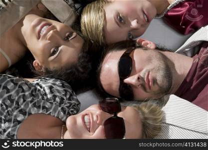Close-up of a young man with three young women lying down