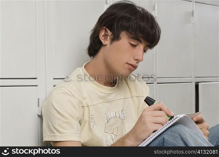 Close-up of a young man writing with a highlighter