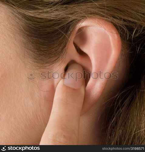Close-up of a young woman&acute;s finger in her ear