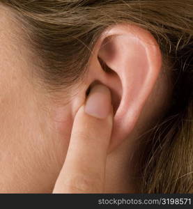 Close-up of a young woman&acute;s finger in her ear