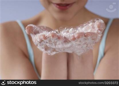 Close-up of a young woman&acute;s hand covered with soap suds