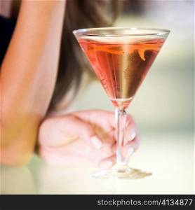 Close-up of a young woman&acute;s hand holding a glass of martini