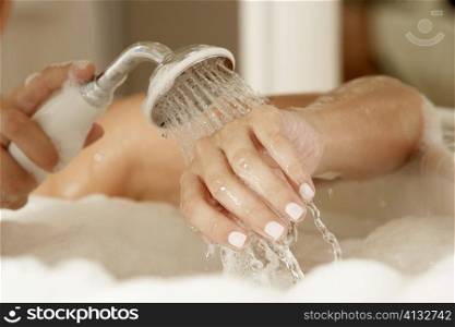 Close-up of a young woman&acute;s hands holding a shower head