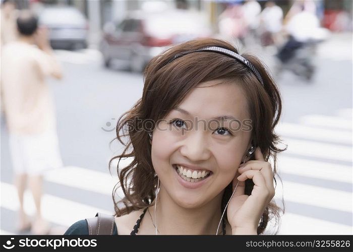 Close-up of a young woman adjusting headphones and looking up