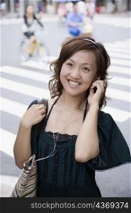 Close-up of a young woman adjusting headphones and looking up