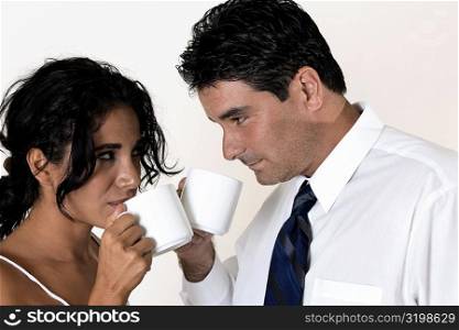 Close-up of a young woman and a mid adult man drinking coffee