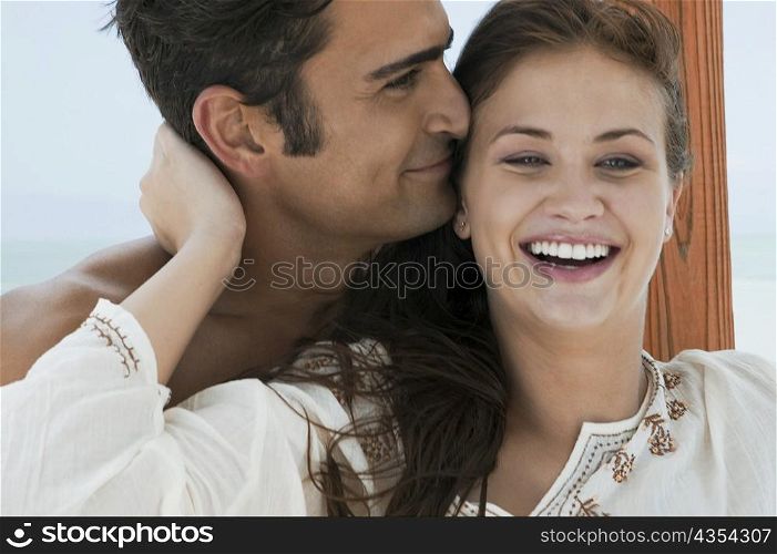 Close-up of a young woman and a mid adult man embracing each other and smiling