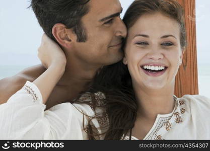 Close-up of a young woman and a mid adult man embracing each other and smiling