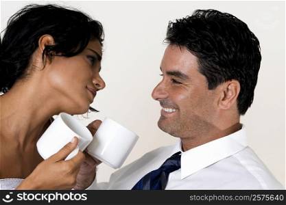 Close-up of a young woman and a mid adult man holding coffee cups