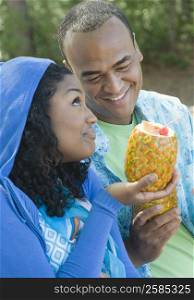 Close-up of a young woman and a mid adult man holding pineapples