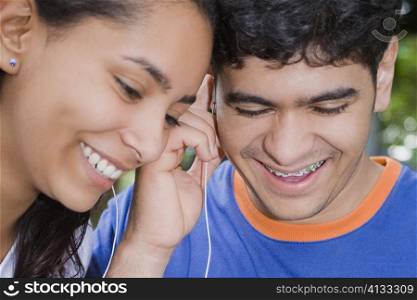 Close-up of a young woman and a mid adult man listening to music and smiling