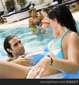 Close-up of a young woman and a mid adult man looking at each other in a swimming pool
