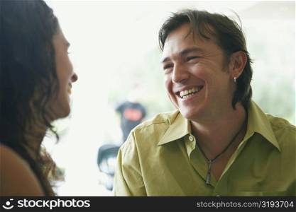 Close-up of a young woman and a mid adult man looking at each other and smiling in a restaurant