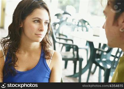 Close-up of a young woman and a mid adult man looking at each other in a restaurant
