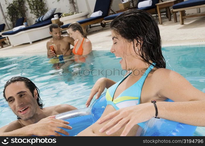 Close-up of a young woman and a mid adult man smiling in a swimming pool