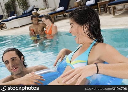 Close-up of a young woman and a mid adult man smiling in a swimming pool