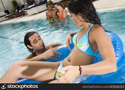 Close-up of a young woman and a mid adult man talking to each other in a swimming pool