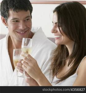 Close-up of a young woman and a mid adult man toasting with champagne flutes