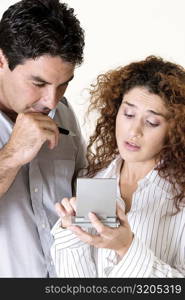 Close-up of a young woman and a mid adult man using a calculator