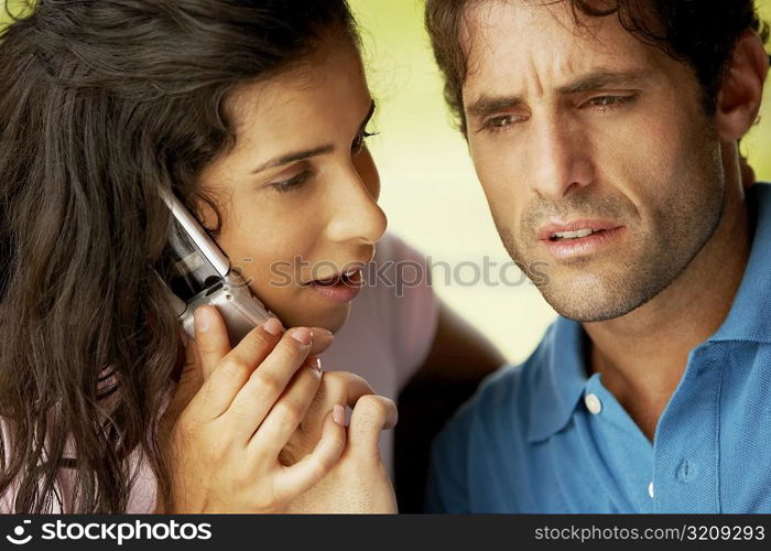 Close-up of a young woman and a mid adult man using a mobile phone