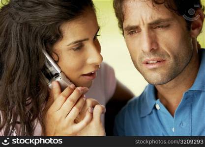 Close-up of a young woman and a mid adult man using a mobile phone
