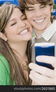 Close-up of a young woman and a teenage boy looking at a mobile phone and smiling