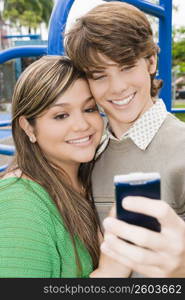 Close-up of a young woman and a teenage boy looking at a mobile phone and smiling