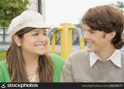 Close-up of a young woman and a teenage boy looking at each other and smiling
