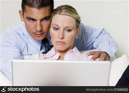 Close-up of a young woman and a young man looking at a laptop