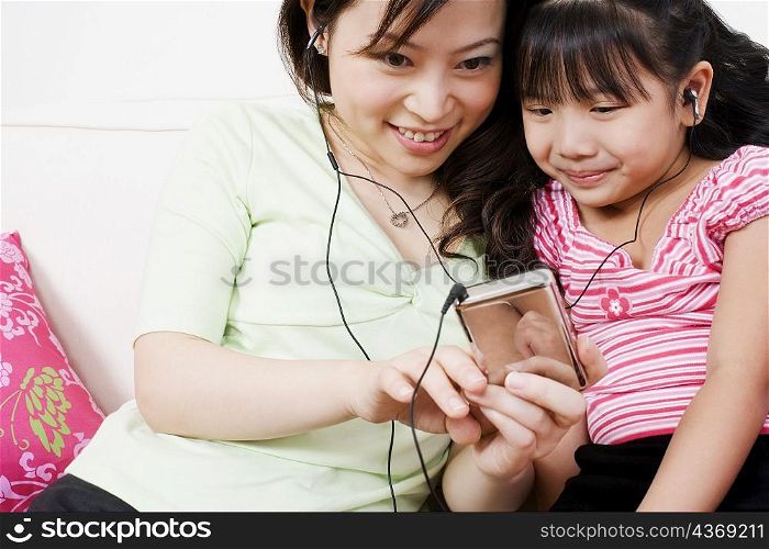 Close-up of a young woman and her daughter listening to an MP3 player