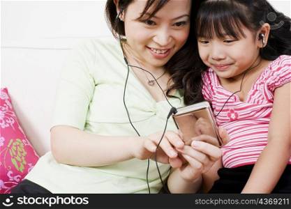 Close-up of a young woman and her daughter listening to an MP3 player