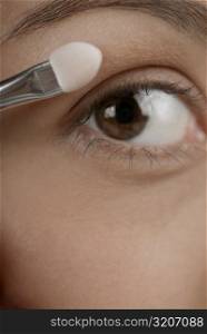 Close-up of a young woman applying eyeshadow
