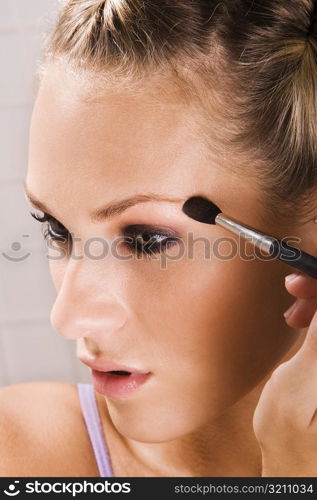 Close-up of a young woman applying eyeshadow