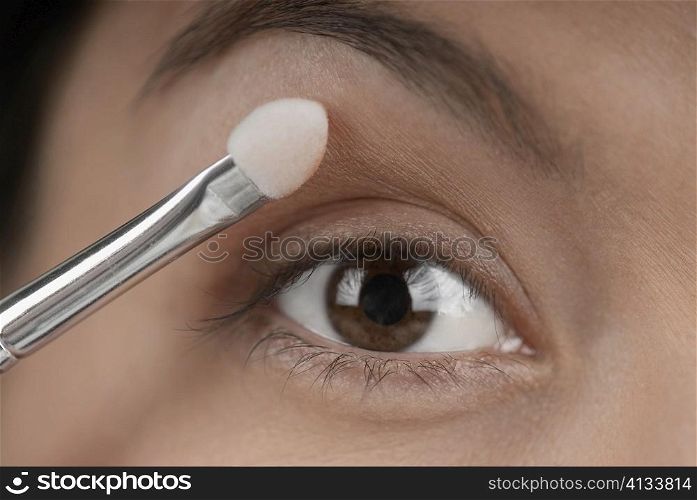 Close-up of a young woman applying eyeshadow