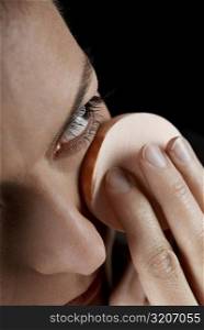 Close-up of a young woman applying face powder with a powder puff