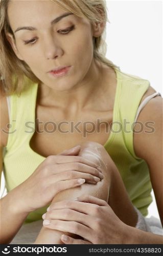 Close-up of a young woman applying hair removing cream on her leg