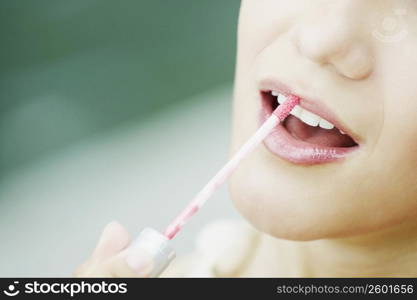 Close-up of a young woman applying lip liner