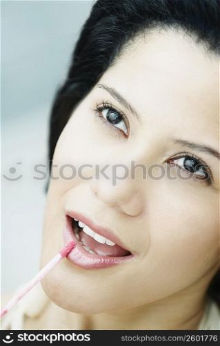 Close-up of a young woman applying lip liner