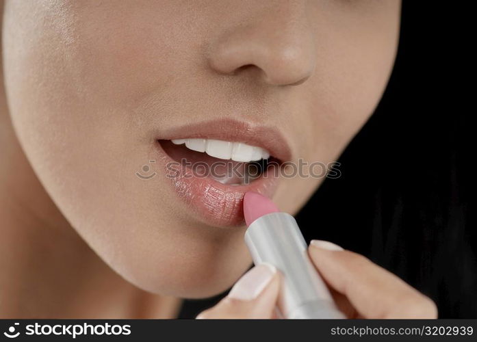 Close-up of a young woman applying lipstick