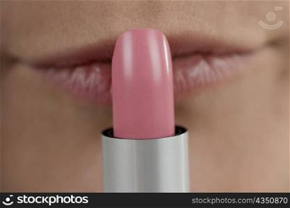 Close-up of a young woman applying lipstick
